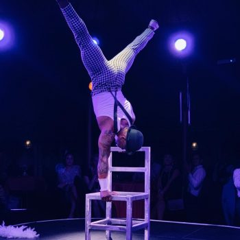 Stuhlakrobatik der Akrobat im Handstand auf Stühlen